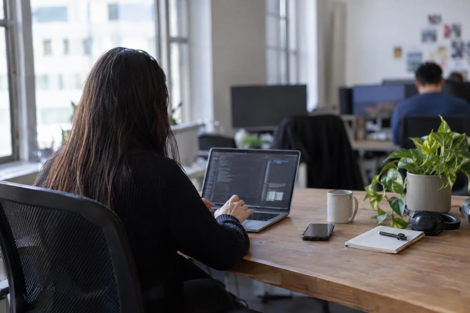 A software developer works at a laptop in an office.