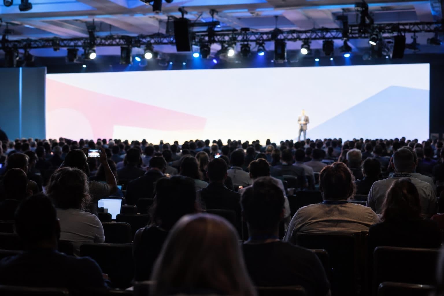 Audience seen from behind watching a presentation on stage at a developer conference