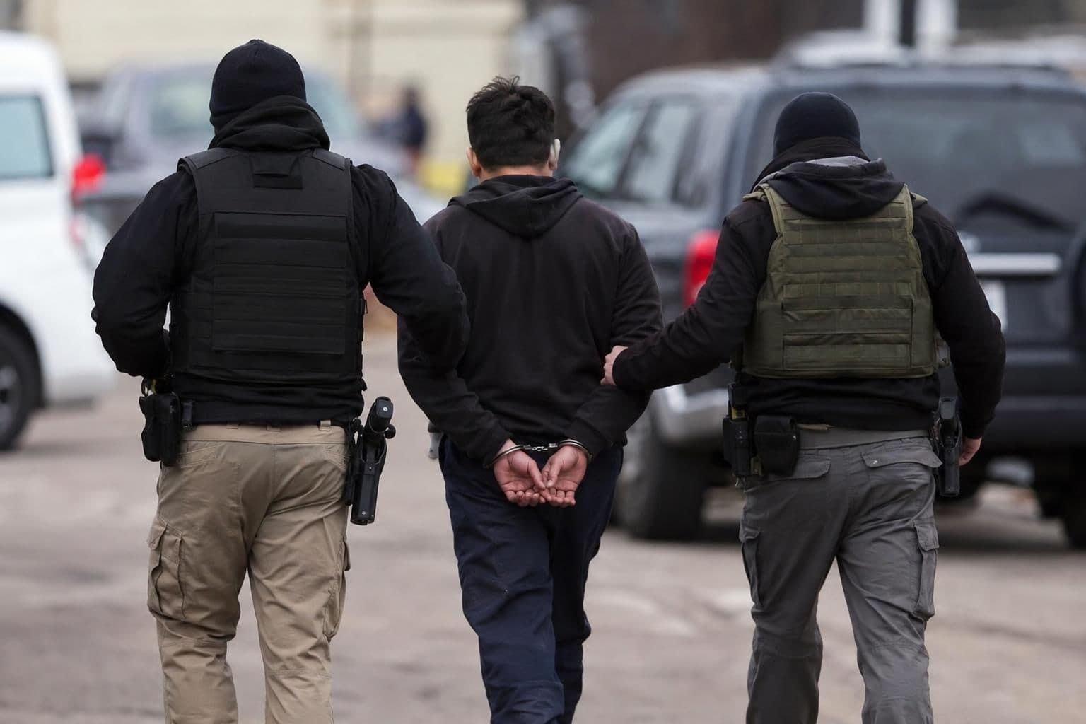 An unidentified man is escorted by officers during an arrest.