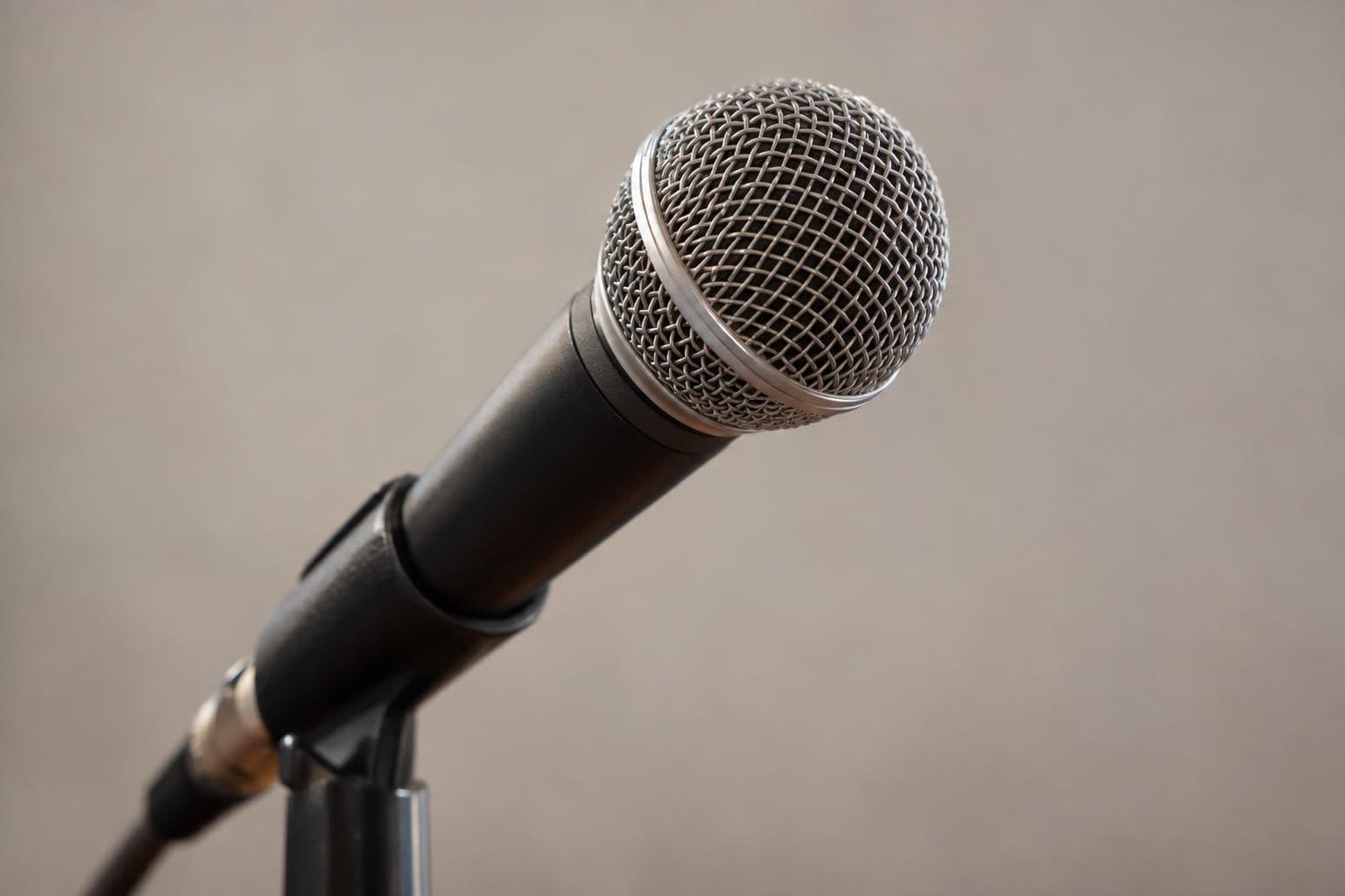 A plain interview microphone isolated against a neutral background.