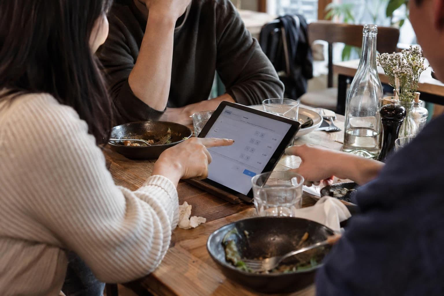 People work together at a table with an interactive bill-splitting calculator open.