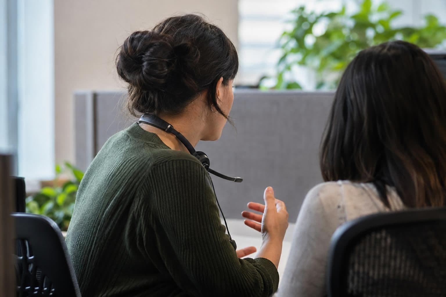 A customer-support representative confers with a colleague about follow-up after a call.