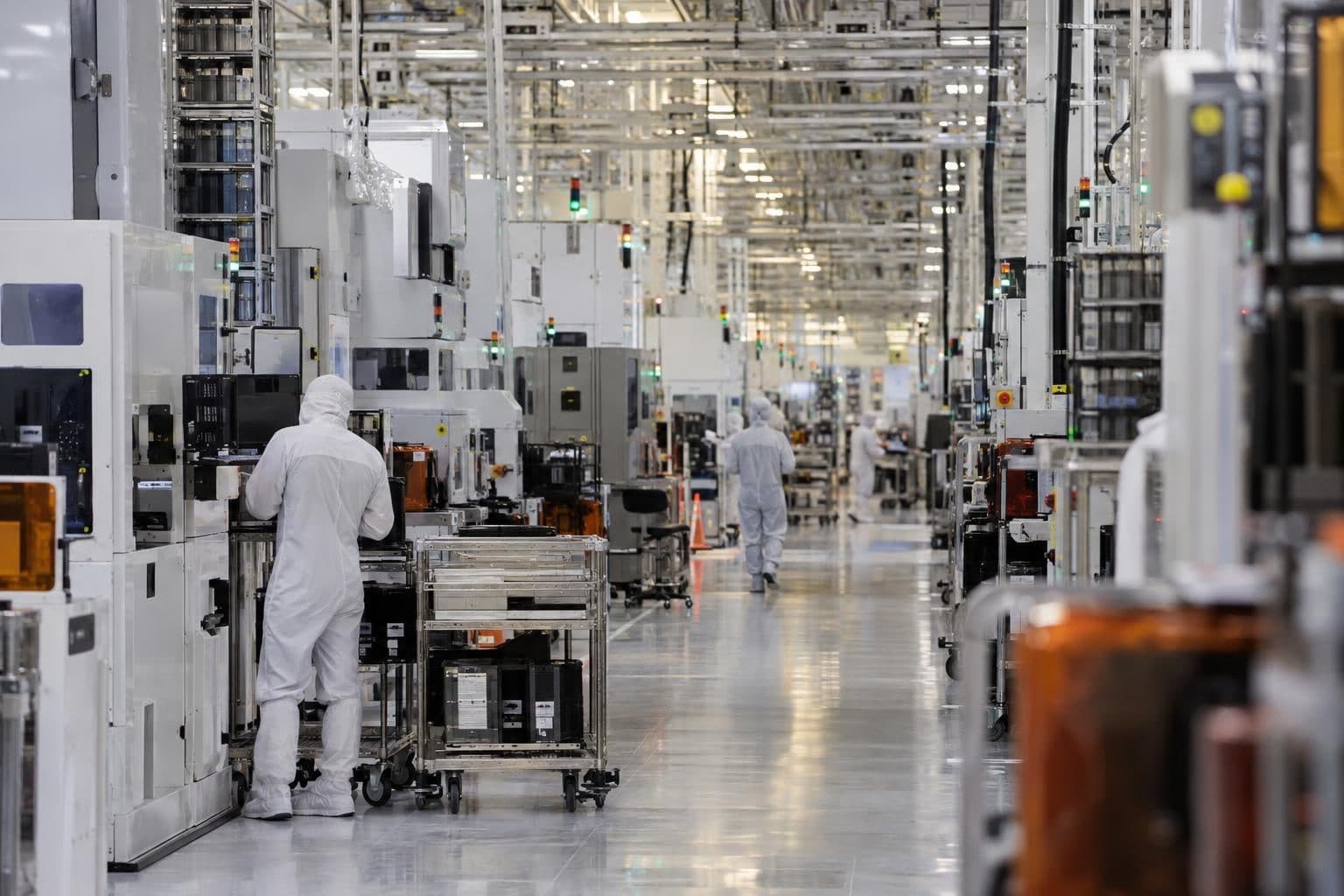 Workers beside manufacturing equipment inside the GlobalFoundries Malta semiconductor fab.