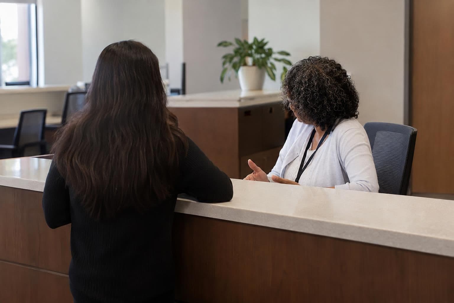A federal agency employee speaks with a visitor across a public-service counter.