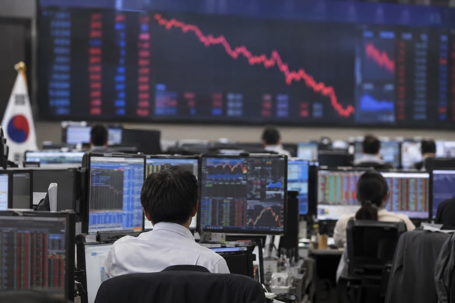 Traders work beneath an electronic market board during a fall in Korean shares.