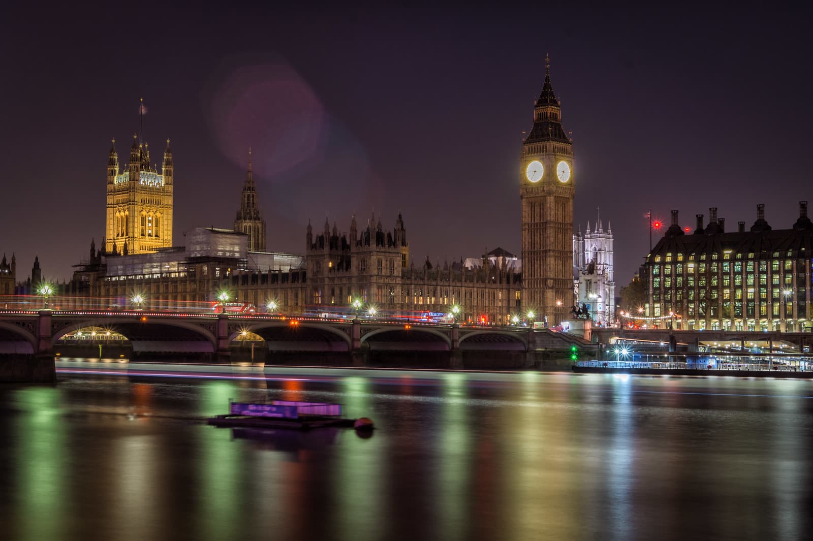 The Palace of Westminster and Big Ben lit at night across the River Thames, with Westminster Bridge in the foreground.